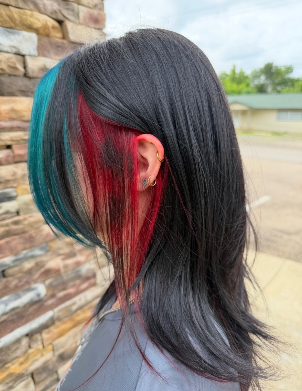 Dark hair with teal and red vivid color panels by Dusty Ozanich