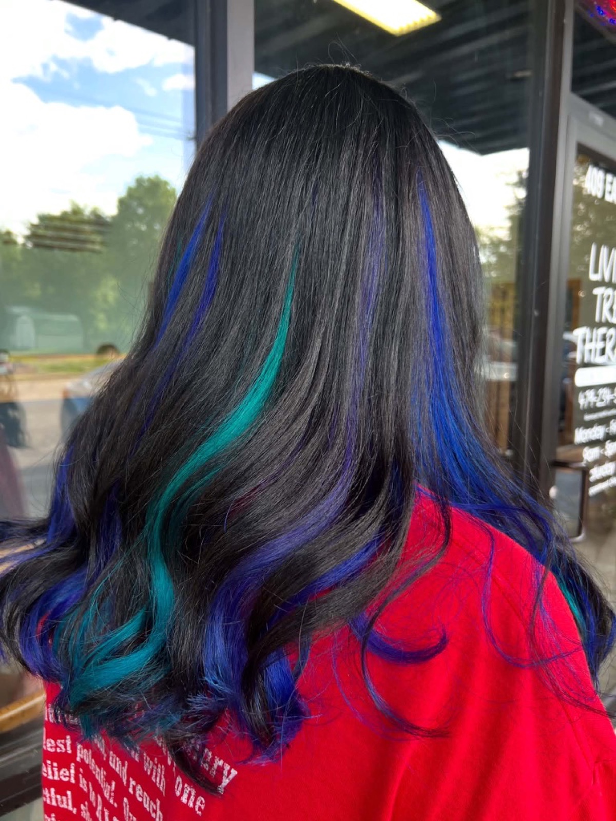 Dark hair with vivid blue, teal, and purple highlights by Jade Ferguson